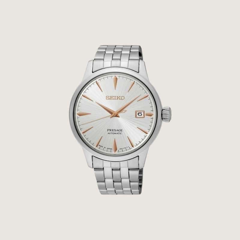 Seiko Presage Cocktail Time with silver sunburst dial, rose gold hands and indices on a stainless steel bracelet, on a plain bone background